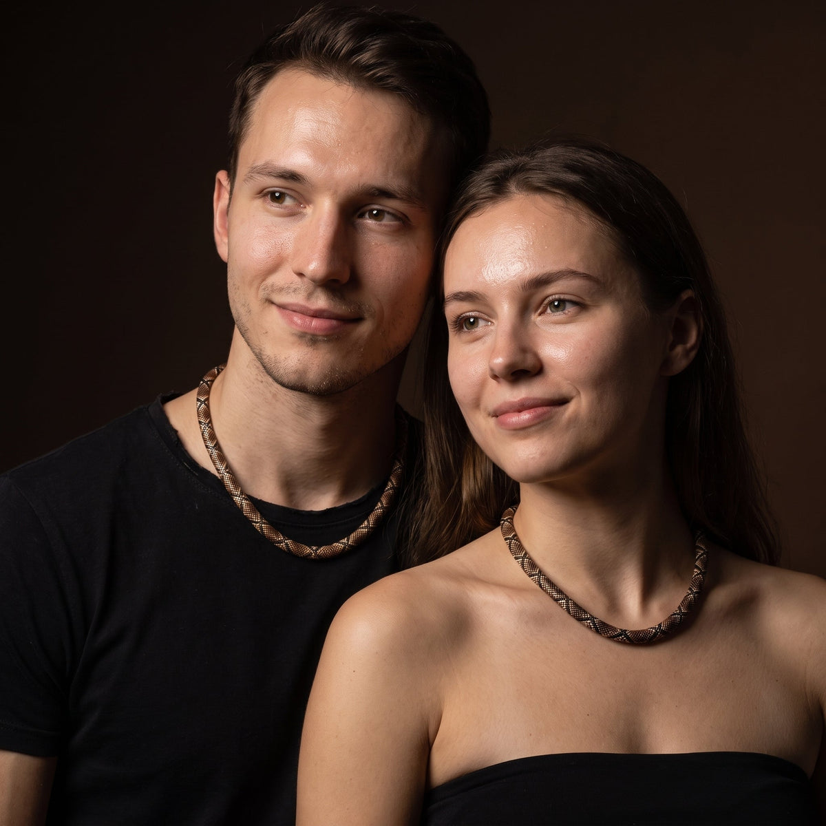 Couple wearing matching serpent necklaces